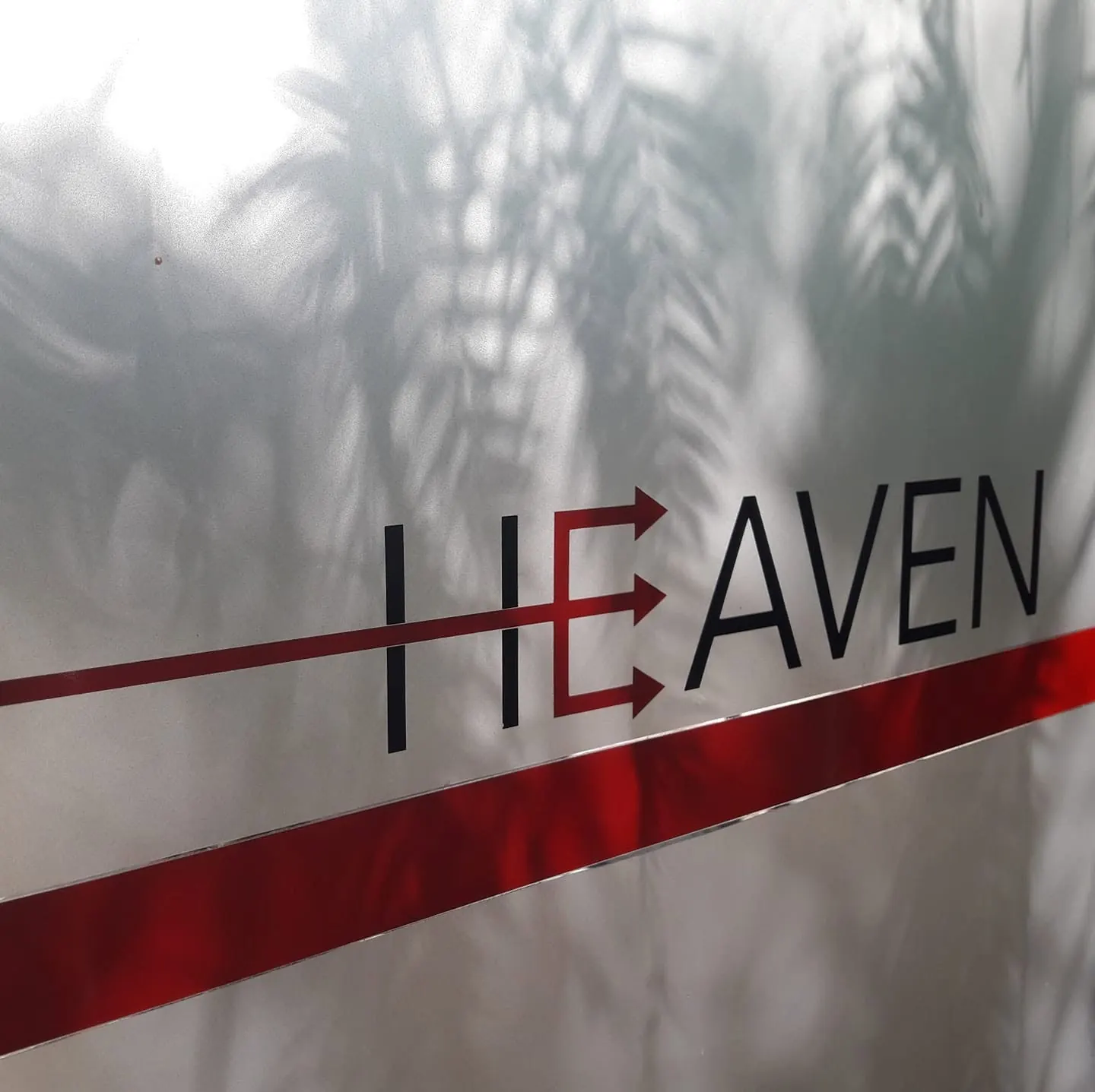 Il logo di Heaven sul muro, con l'ombra delle palme